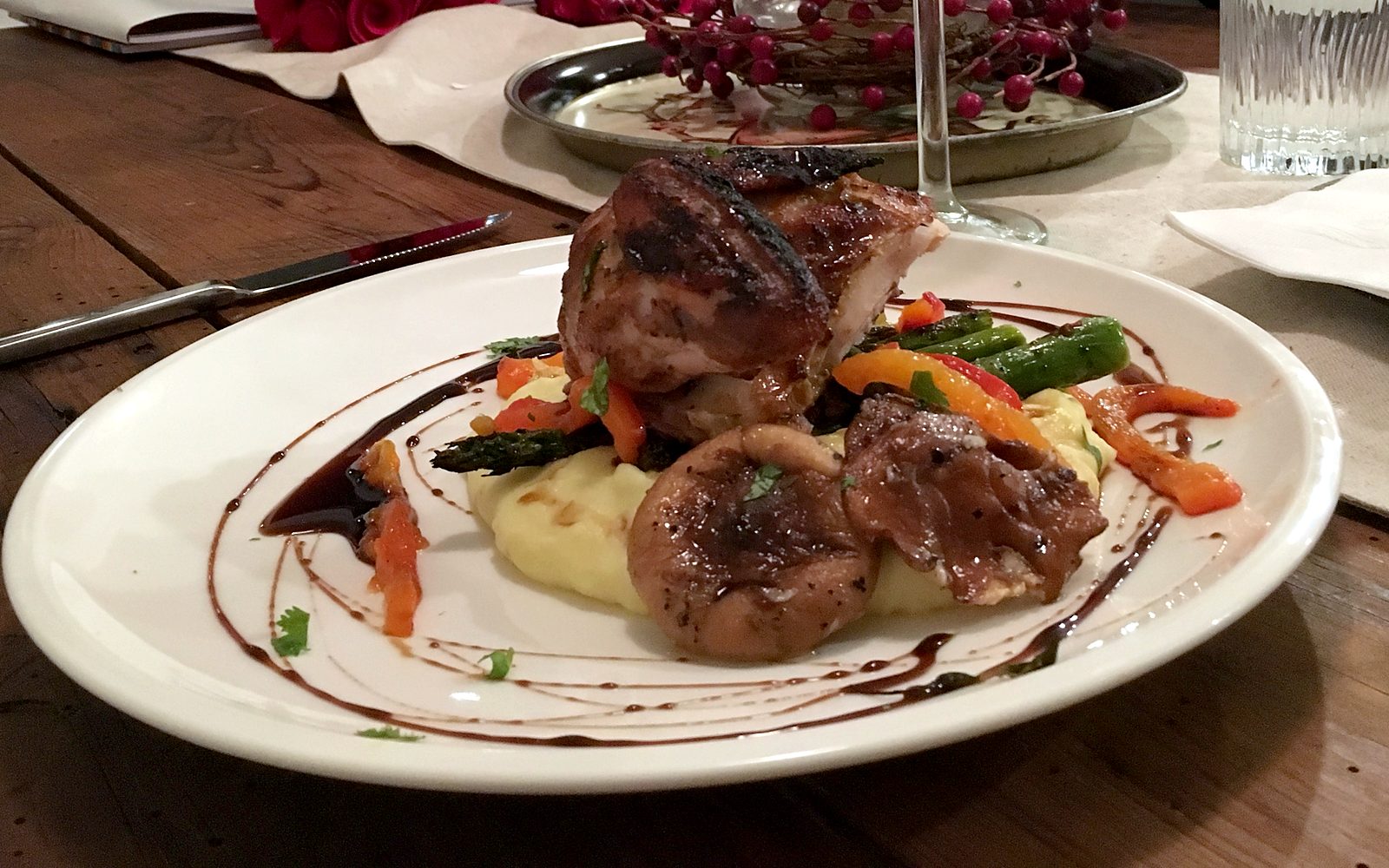 Plated dinner over potato purée with asparagus, roasted peppers and a dark reduction